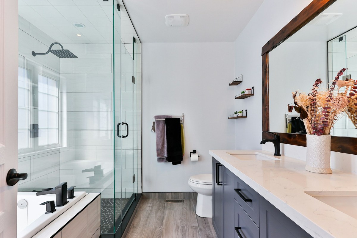 Modern bathroom with glass shower, white subway tile, grey vanity, and large wood-framed mirror